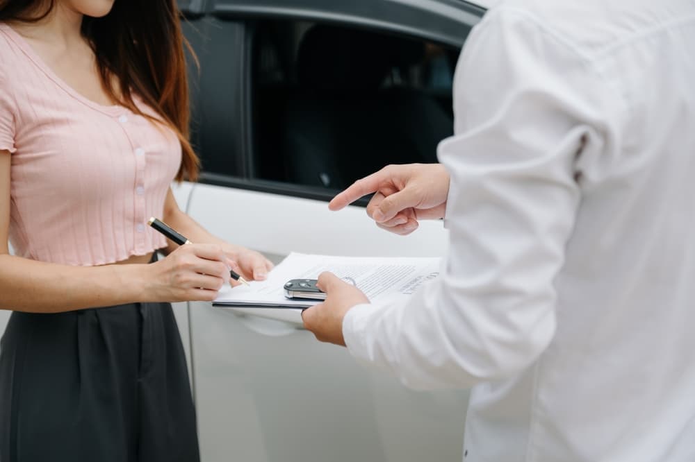 A women signing car accident claim papers given to her by a insurance representative.