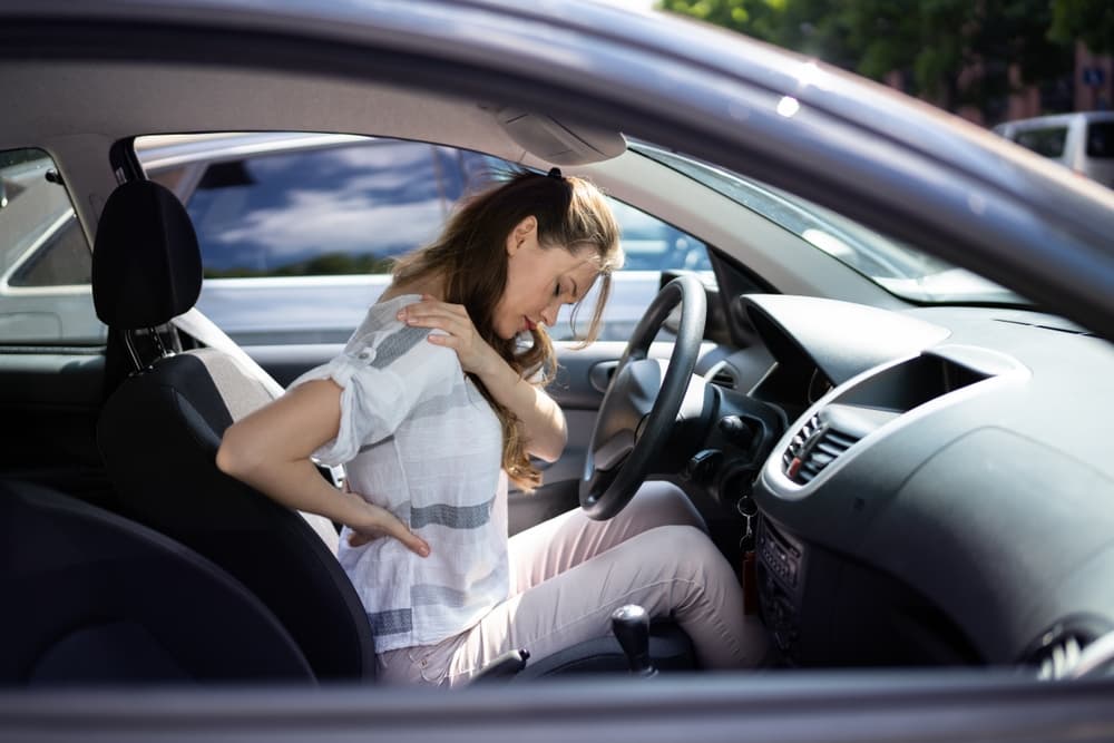 A woman in New London, CT suffered back and neck injuries after a car collision. She was sitting in her car after the accident, holding her back and neck.