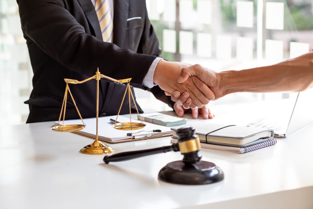 Business concept: Lawyers in a team meeting at a law firm, lawyer shaking hands, and judge gavel symbolizing justice.