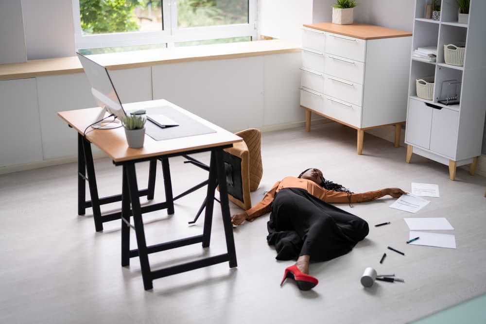 Full-length view of a young businesswoman who has fallen off her office chair.